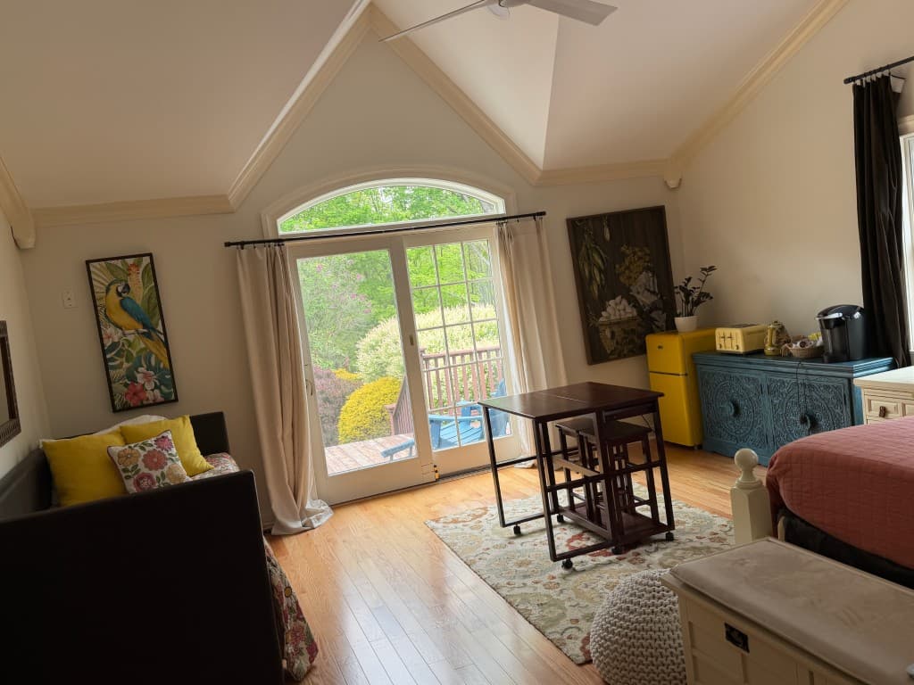 Vaulted studio living area with deck access and garden views